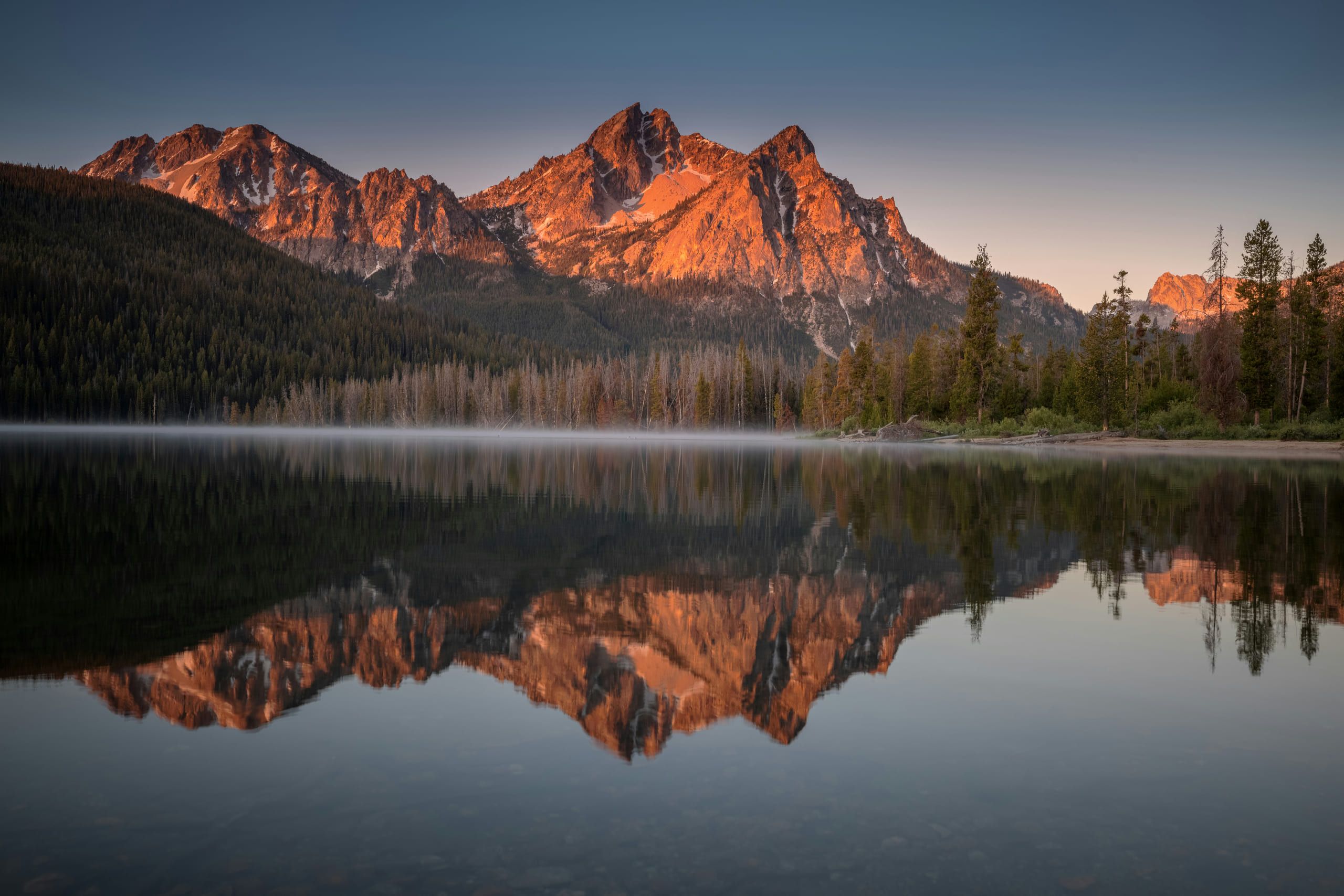 Alpengloed op de Sawtooth Mountains, gespiegeld in een meer